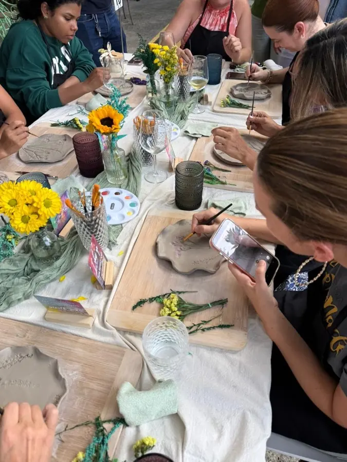 Invitadas pintando sus piezas de cerámica con flores en la mesa