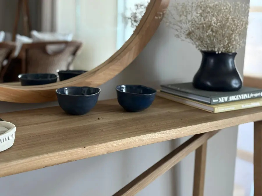 Bowls de cerámica azul y florero negro sobre una mesa de madera