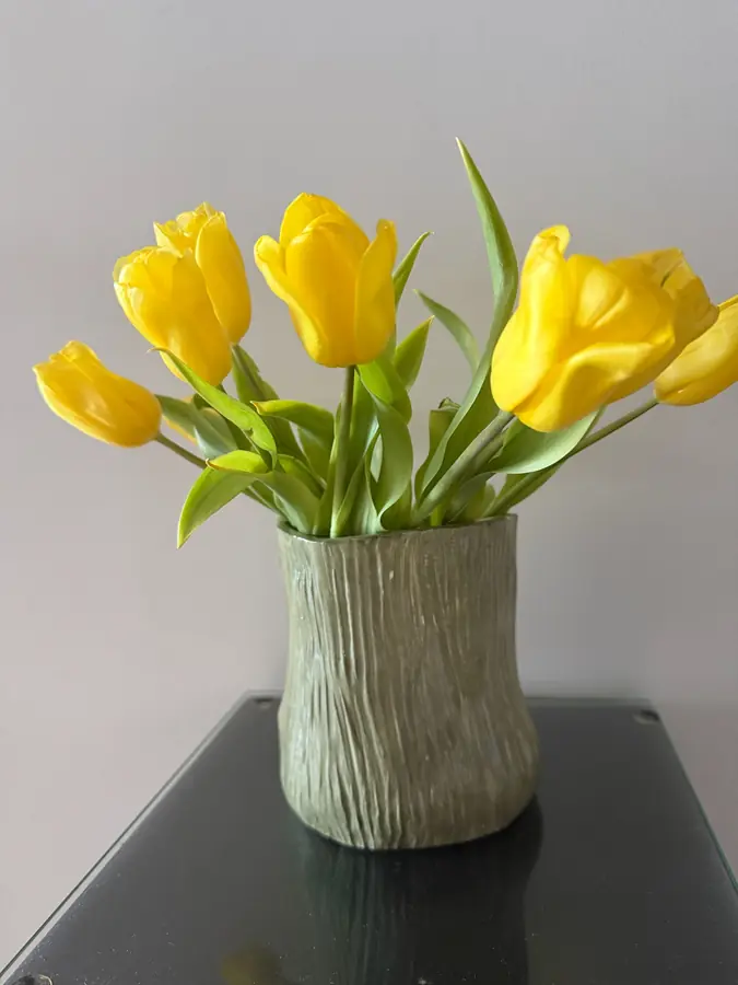 Florero de cerámica verde texturado con tulipanes amarillos