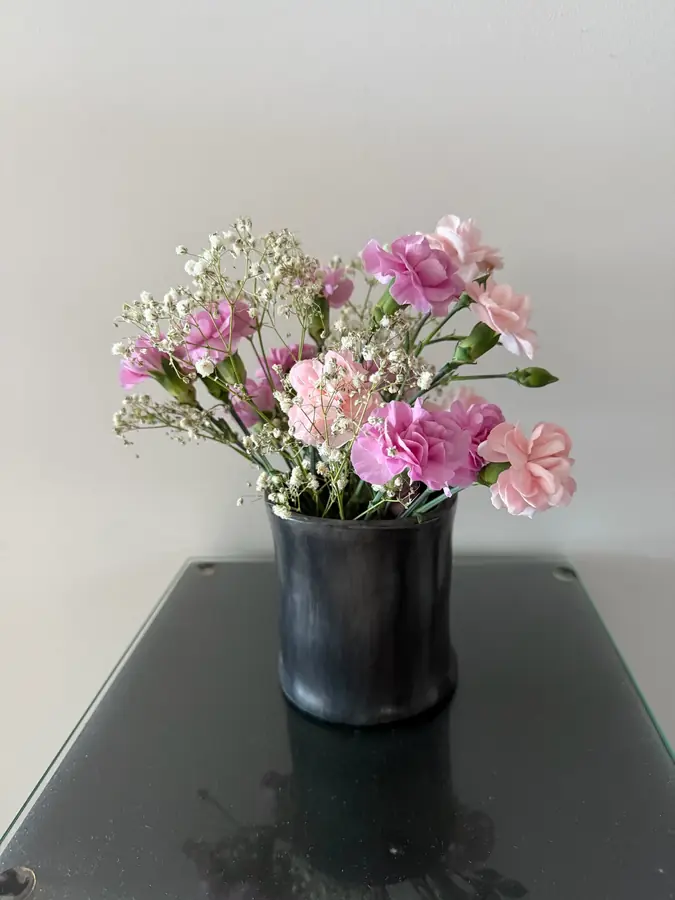 Florero de cerámica negro con flores rosadas