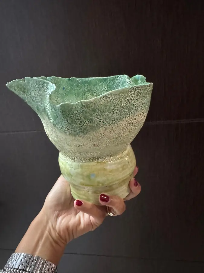 Florero de cerámica verde con forma libre, sostenido en la mano